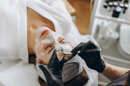 Close up of cosmetologist make face mask for woman client in saloon.Dermatology,beauty concept. High quality photoの写真素材