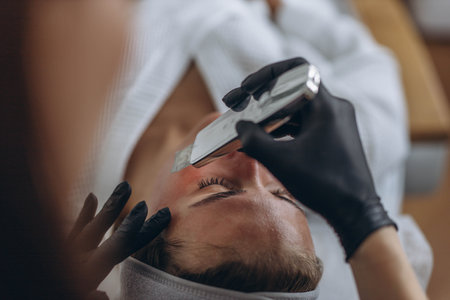 Cosmetologist making facial treatment with ultrasonic spatula to young woman. . High quality photo