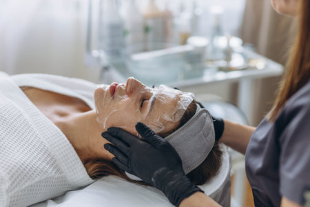 Cosmetologist cleanses young woman's face using professional skincare products. High quality photoの写真素材