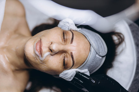 Middle aged woman receiving facial cleansing and care at a cosmetologist office. High quality photoの写真素材