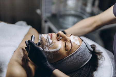Middle aged woman receiving facial cleansing and care at a cosmetologist office. High quality photoの写真素材