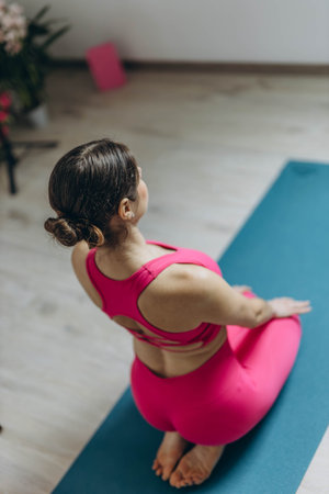 Cute sporty woman in pink leggings doing yoga exercises in a bright room. High quality photo