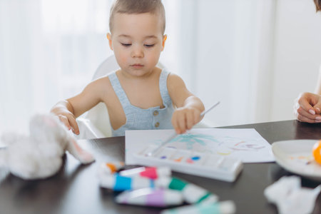 Little boy sitting in high chair,painting with bright colors on paper.Creative childhood momentの写真素材
