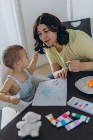 Little boy painting with his mother, enjoying creative moment together. Motherhood, parenting conceptの写真素材