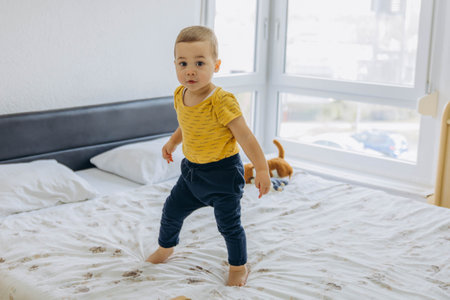 Two year old boy jumping and playing on the bed, full of energy and joy. High quality photoの写真素材