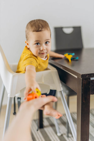 Cute Baby boy sitting in a high chair, playing with mom, capturing a sweet parenting moment. High quality photoの写真素材