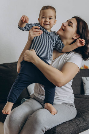Two year old cute boy sitting in his mother's arms, both smiling and enjoying a joyful moment together. High quality photoの写真素材