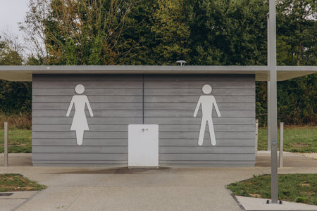 Public restroom building with male and female symbols on a wooden facade. Outdoor sanitation facility, accessible toilet at rest area. High quality photoの写真素材