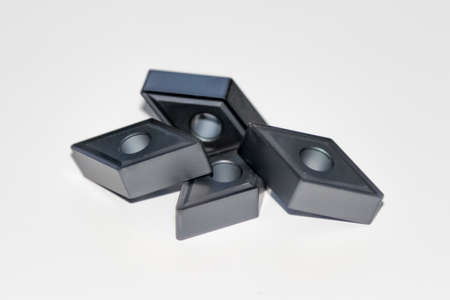 Closeup of four carbide inserts for CNC milling machine with selective focus isolated on white