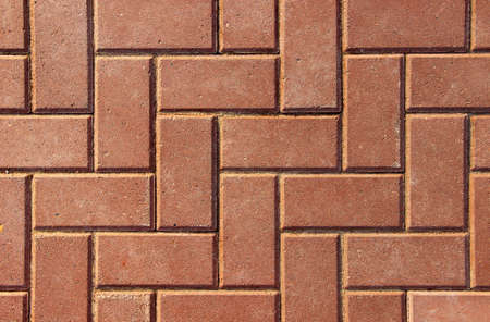 Sidewalk paved with rectangular red tiles in harmonic structure as a background