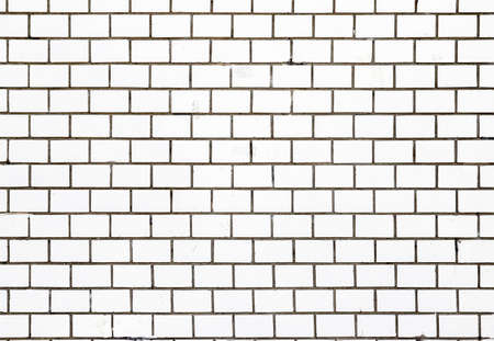 Texture of an old damaged wall made of white rectangular tiles as a background