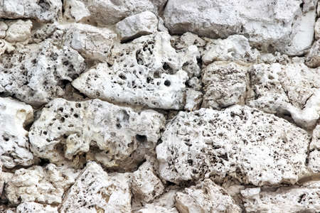 Wall made of naturally perforated stones as a backgroundの写真素材