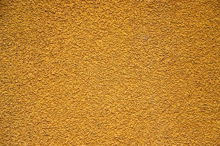 Texture of a plasterwork painted in yellow used as an exterior coating on a building as a backgroundの写真素材