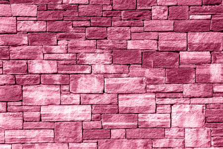 Texture of a stone wall made of rectangular blocks of different sizes painted in pink as a backgroundの写真素材
