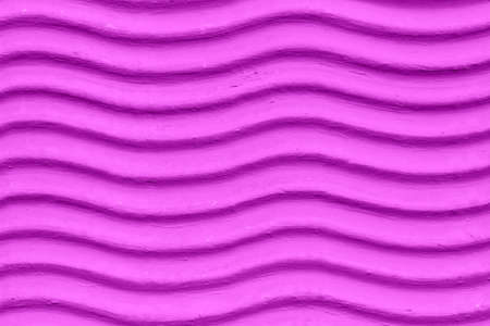A decorative wall with a wavy structure painted in violet as a backgroundの写真素材