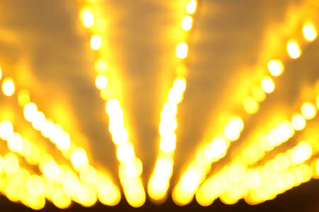 Golden festive background. Blurred yellow holiday lights in perspective