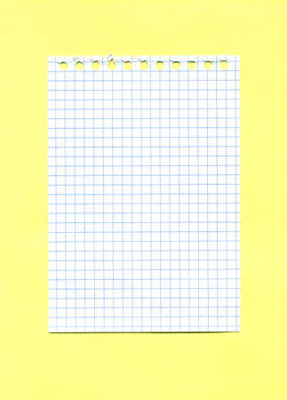 Checked paper sheet torn out of a spiral notebook isolated on yellow background. Minimalistic mockup with copy space.の写真素材