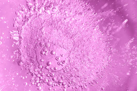 Thick ice with frozen air bubbles. Pink colored background. Closeup photo.