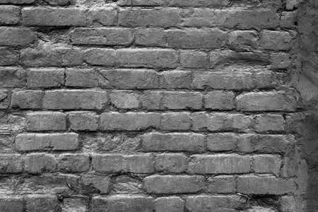 Texture of an old and damaged brick wall coated with black paint as a backgroundの写真素材