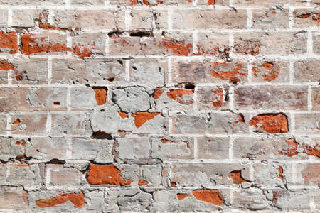 Texture of an old damaged brick wall partially covered with old cracked plasterwork