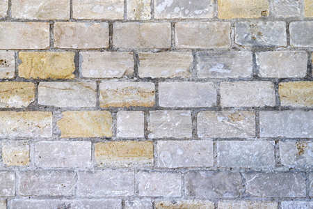 Texture of an old damaged wall made of white, gray and yellow bricks as a backgroundの写真素材