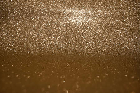 Sparkling golden glittery background for holiday, luxury, fashion designs. Photo in perspective with selective focus.の写真素材