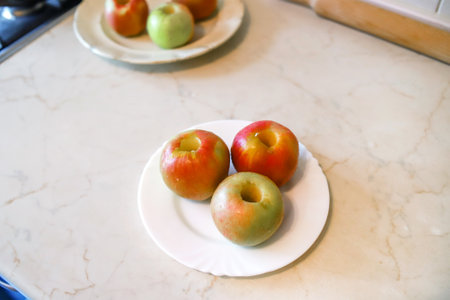Closeup of the three ripe red and yellow apples with removed core on the white plateの写真素材