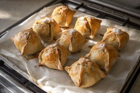 Making apples baked in dough. Yummy hot pastry items with white sugar on top on baking sheet