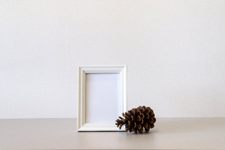 Mock up minimalist home interior with empty white wooden photo frame and big pine cone. Photo with copy spaceの写真素材