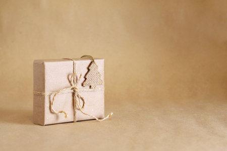 Zero waste Christmas. Handmade brown paper gift box with Cristmas ornament made of sackcloth on brown paper background. Backdrop with copy space.の写真素材