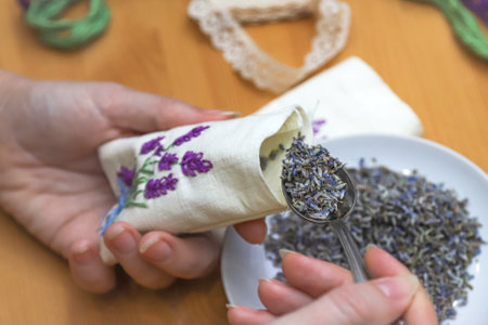 Making lavender sachet with floral embroidery at home on wooden background. Zero waste DIY gift. Homemade aromatherapy. Photo with selective focusの写真素材