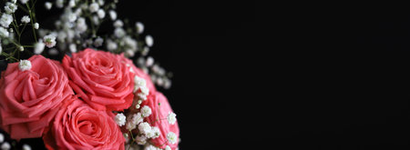 Closeup of a delicate pastel pink bunch of roses decorated with small white flowers on black background. Beautiful bouquet as a romantic web banner with copy space. Photo with selective focusの写真素材