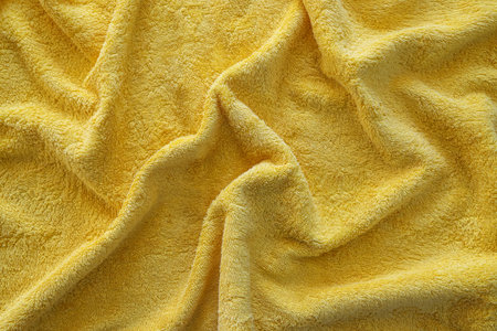Texture of a wavy surface of a yellow terry fabric as a backgroundの写真素材