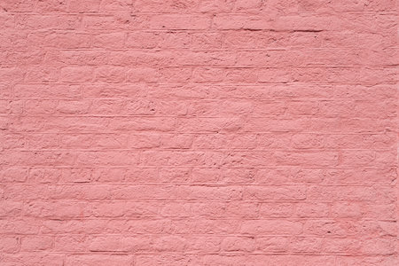 Closeup texture of a brick wall coated with the thick layer of pastel pink paint as a romantic architectural backgroundの写真素材