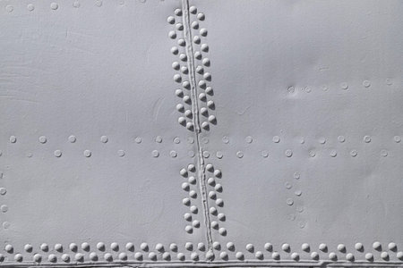 Closeup of the riveted with button-head rivets metal plate - side of an aircraft - painted in gray...