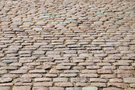 Closeup of an old weathered stoneblock pavement cobbled with heavily worn rectangular blocks. Photo...