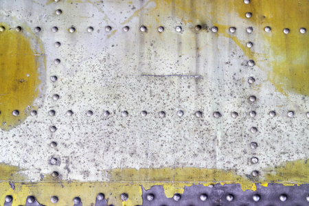 Close-up of a metal sheet with rivets and peeling paint. Scratches and wear create a vintage look....