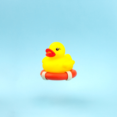 Safety equipment, life buoy or rescue buoy and duck toy on blue background, minimal summer concept