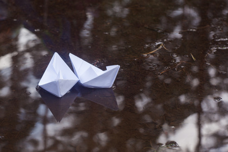 Two paper boats in a puddle in autumnの写真素材