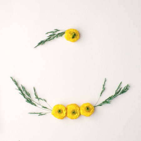 Flowers composition. Wreath made of various yellow flowers and green leaves and branches on pastel...