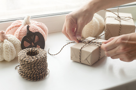 Autumn background. Hands packing gift box for halloween party, autumn knitted decoration on white backgroundの写真素材