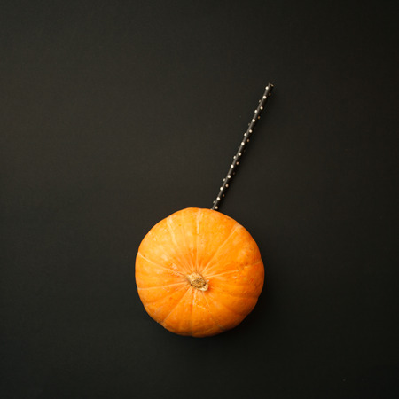 Concept of Halloween pumpkin orange cocktails on mystery black background. Festive drink, minimal trendの写真素材