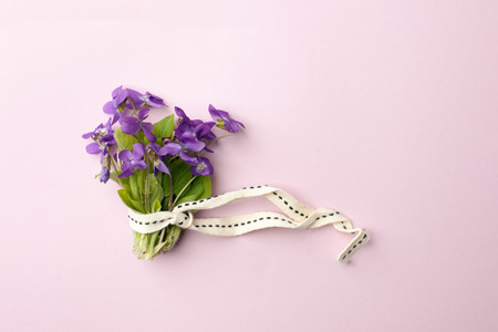 violet flowers in bouquet on pink background, flat lay. Spring, summer romantic minimal conceptの写真素材