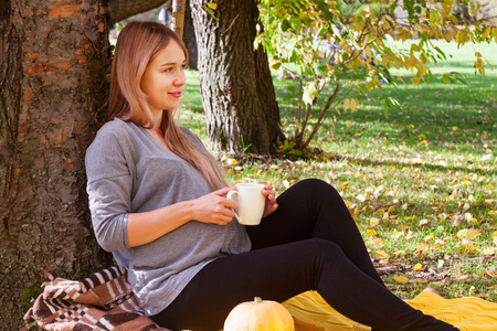 pregnant woman resting in an autumn parkの写真素材