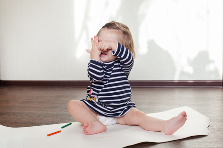 little girl is sitting on the floor, having fun, pick a booの写真素材