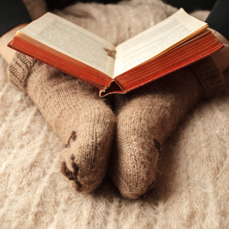 Cozy Winter fall autumn lifestyle: woman in warm cute bear socks with  book. Retro toning, beige monochrome, hipster still lifeの写真素材