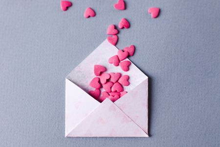 Envelope with heap of small hearts on gray background. Valentines Day concept. Top viewの写真素材