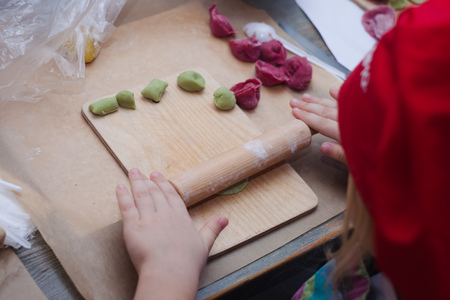 stages of cooking a meat dish - dumplings made from dyed dough. Children's hands work with dough and raw minced meatの写真素材