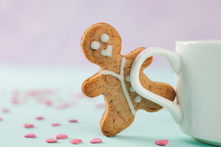 loving gingerbread man stands near a white mug, copy space