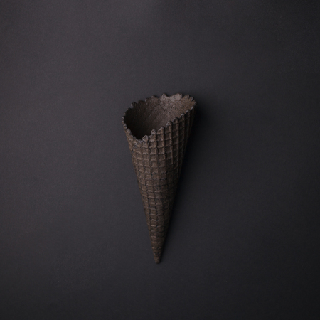 Empty Black Ice Cream Cone on black background, monochrome minimal closeupの写真素材